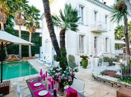 Villa Roses d'Antibes: looking across the terrace from a table set with 4 places to the front of this pretty art deco house with the pool and sun loungers to the left.