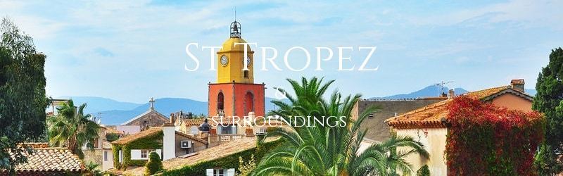 A view across the rooftops past a colourful clock tower to the hills behind St Tropez in the South of France